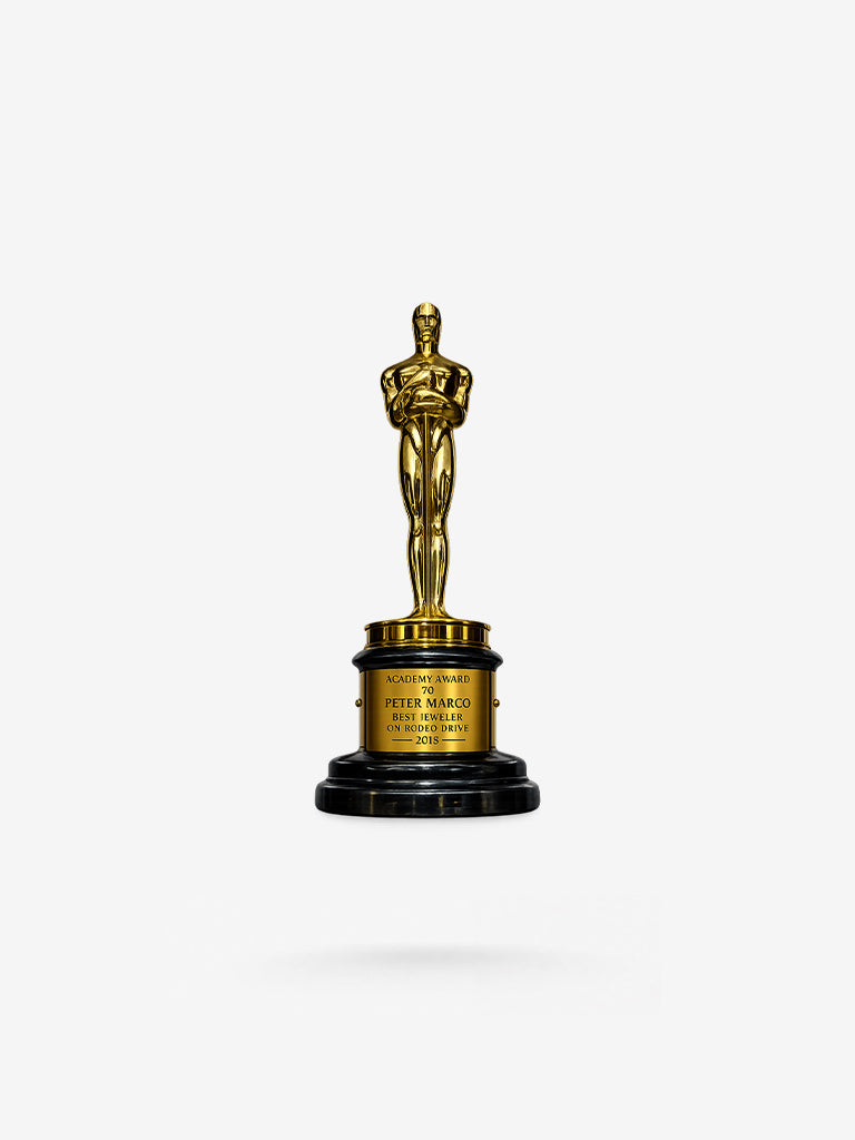 An Academy Award Best Jeweler trophy featuring a gold-toned Oscar statue on a black circular base with a gold engraved plaque reading 'ACADEMY AWARD 70 PETER MARCO BEST JEWELER ON RODEO DRIVE 2018'.
