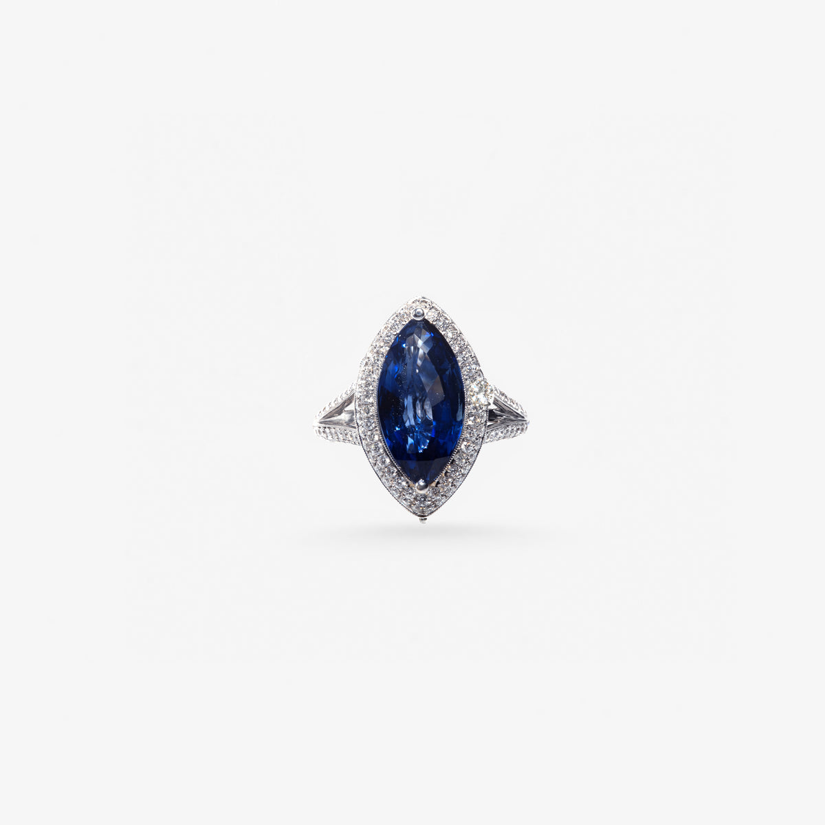 Peter Marco blue sapphire ring surrounded by a white diamond halo with diamond-set band